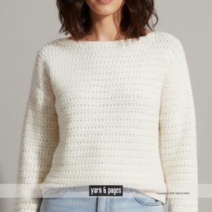 Può includere: Maglione all'uncinetto color crema a maniche lunghe con scollo a barchetta. Il maglione presenta un motivo a punto orizzontale strutturato. La parte inferiore del maglione è visibile, insieme al testo "yarn & pages" in un riquadro bianco.