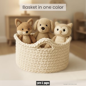 Puede incluir: Una cesta tejida de color crema contiene tres juguetes de peluche: un zorro, un perro y un b&uacute;ho. La cesta tiene dos asas y el texto "Basket in one color" est&aacute; encima de la cesta. La parte inferior de la imagen tiene el texto "yarn & pages".