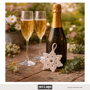 May include: A celebratory scene featuring two champagne flutes filled with bubbly liquid, a dark bottle with a gold foil top, and a white snowflake ornament. The items are arranged on a wooden surface, with flowers in the background.