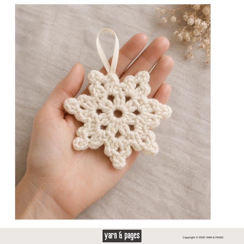 May include: A cream-colored, crocheted snowflake ornament with a loop for hanging. The snowflake has a detailed, openwork design and is held in a hand. The ornament is a handmade item, perfect for holiday decor.