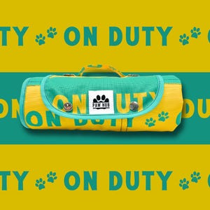 May include: A yellow and teal dog treat bag with the text "ON DUTY" and paw prints. The bag has a handle and a flap closure with two silver press studs. The Paw Hub logo is on the front.
