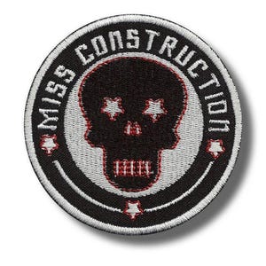 Könnte beinhalten: Runder, schwarz-weißer, gestickter Aufnäher mit dem Schriftzug "MISS CONSTRUCTION". In der Mitte befindet sich ein schwarzer Totenkopf mit sternförmigen Augen und roten Akzenten.