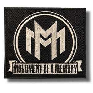 Puede incluir: Parche cuadrado negro con un diseño bordado en blanco. El diseño presenta dos formas estilizadas de "M" blancas dentro de un círculo blanco, con las palabras "MONUMENT OF A MEMORY" en blanco en una pancarta debajo.