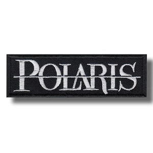 Può includere: Toppa rettangolare nera ricamata con la scritta "POLARIS" in bianco, in lettere maiuscole stilizzate. Il testo è centrato e diviso orizzontalmente da una linea bianca. La toppa ha un bordo nero.