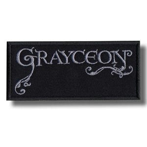 May include: A set of three ceramic mugs with a speckled, matte finish. The mugs are in shades of cream, light gray, and dark gray. Each mug has a simple, minimalist design and a rounded handle.