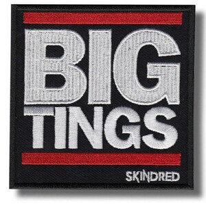 May include: Black square patch featuring the words "BIG TINGS" in white embroidery, with a red stripe above and below. The brand name "SKINDRED" is embroidered in white at the bottom of the patch.