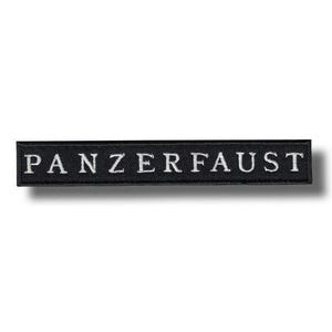 May include: A black rectangular patch embroidered with the word "PANZERFAUST" in white capital letters. The patch is slightly raised, casting a shadow.