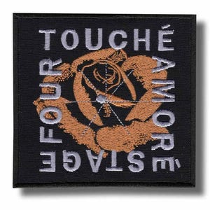 Könnte beinhalten: Schwarzer quadratischer Aufnäher mit gesticktem Text und Rosendesign. Der Text lautet "TOUCHÉ AMORE" und "FOUR STAGE" in silbernem Faden. Die Rose ist in Braun- und Beigetönen gehalten, mit einem netzartigen Design in der Mitte.