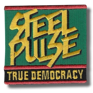Peut inclure: Écusson brodé carré avec les mots "FEEL PULSE" en fil doré sur fond vert. L'écusson a une bordure rouge et le texte "TRUE DEMOCRACY" en noir. L'écusson a une légère ombre.