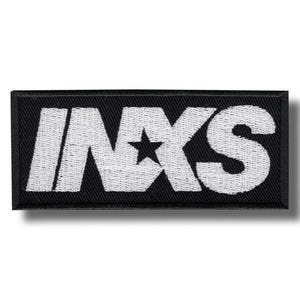 Könnte beinhalten: Schwarzer rechteckiger Aufnäher mit dem weißen gestickten Text "INXS" und einem Stern in der Mitte. Der Aufnäher hat einen schwarzen Rand und ist zum Aufnähen oder Aufbügeln auf Kleidung oder Accessoires gedacht.