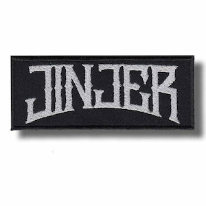 May include: Black rectangular patch with the word "JINJER" embroidered in white, stylized, gothic lettering. The patch has a black border and a slight shadow effect, suggesting a raised design. The text is arched.