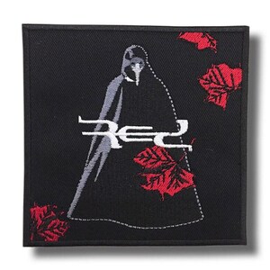 Puede incluir: Parche cuadrado negro con un diseño bordado. El parche presenta una figura con una capa con capucha, la palabra "Red" en blanco y hojas de arce rojas. El diseño está delineado con costuras blancas.