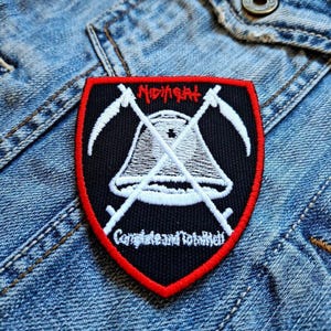 Könnte beinhalten: Ein schwarzer und roter Aufnäher mit dem Wort "Midnight" über einer weißen Glocke und gekreuzten Sicheln. Der Text "Complete and Total Hell" befindet sich darunter. Der Aufnäher befindet sich auf einer Jeansjacke.