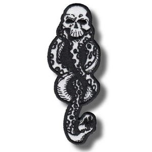 May include: Embroidered patch featuring a black skull intertwined with a snake on a white background. The patch has a detailed design with a skull at the top and a snake body with patterned scales. The edges are neatly stitched.