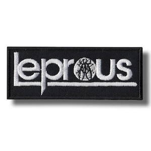 Puede incluir: Parche rectangular negro con la palabra "LEPROUS" bordada en blanco, con un diseño estilizado en el centro. El parche es probablemente para ropa o accesorios.