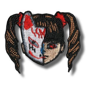 Op de afbeelding: Geborduurde patch met een gespleten gezichtsontwerp. Eén kant toont een wit en rood masker, de andere een realistisch gezicht met rode ogen. De patch heeft zwart haar gestyled in staartjes met rode accenten.