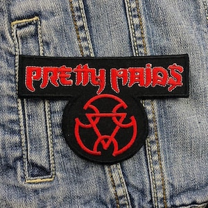 Könnte beinhalten: Schwarz-roter gestickter Aufnäher mit dem Text "PRETTY MAIDS" über einem kreisförmigen Emblem. Der Aufnäher ist auf eine Jeansjacke genäht. Der Text und das Emblem sind rot.
