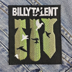 Puede incluir: Parche bordado con el texto "BILLY TALENT" en blanco. El parche presenta tres bombas verdes con pájaros blancos y negros. El parche está sobre un fondo de mezclilla.