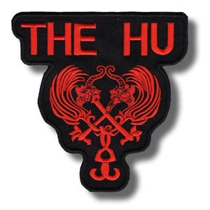 May include: Black patch with red embroidered text "THE HU" at the top. Below the text is a red emblem featuring two stylized dragons with crossed swords. The patch has a unique shape with a curved bottom.