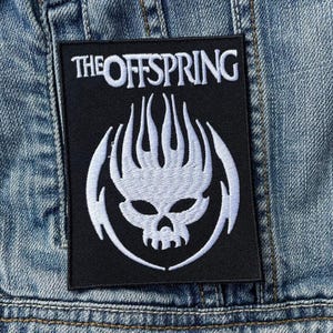 May include: Black rectangular patch with the text "THE OFFSPRING" in white above a white skull design with flames. The patch is sewn onto a denim jacket.