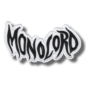 May include: Embroidered patch with the word "MONOLORD" in black, stylized lettering. The patch has a white border and a slight shadow effect, giving it a raised appearance. The patch is likely for clothing or accessories.