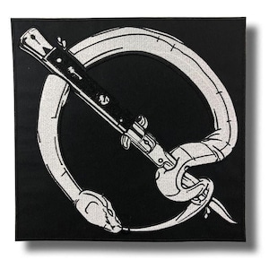 Pode incluir: Patch quadrado preto com um desenho bordado branco. Apresenta uma cobra enrolada em volta de uma faca de mola preta. A cabeça da cobra está na parte inferior esquerda, com a faca em ângulo.