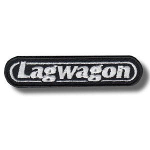 May include: Black rectangular patch with the word "Lagwagon" embroidered in white. The patch has a white border and a black background. The patch is a rectangle with rounded corners.