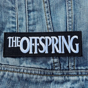 Puede incluir: Un parche rectangular negro con el nombre de la banda "THE OFFSPRING" bordado en blanco y azul claro. El parche está cosido en una chaqueta vaquera azul, con costuras y textura de tela visibles.