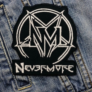 Könnte beinhalten: Schwarzer Aufnäher mit weißem Stickdesign. Der Aufnäher zeigt ein stilisiertes Emblem mit dem Text "Nevermore" in Weiß. Der Aufnäher ist wahrscheinlich für eine Jacke oder eine Tasche.