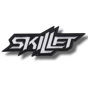 Könnte beinhalten: Ein schwarz-weißer, gestickter Aufnäher mit dem Wort "SKILLET" in einer stilisierten, eckigen Schriftart. Der weiße Text ist schwarz umrandet und vor einem schwarzen Hintergrund platziert. Der Aufnäher hat eine einzigartige, geometrische Form.