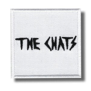 May include: Square white patch with a stitched border. The text "THE CHATS" is embroidered in black, with a lightning bolt replacing the letter "S". The patch has a textured surface.