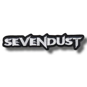 Puede incluir: Parche bordado con el nombre de la banda "SEVENDUST" en letras blancas estilizadas. El parche tiene un borde negro y está sobre un fondo blanco. El diseño es de forma rectangular.