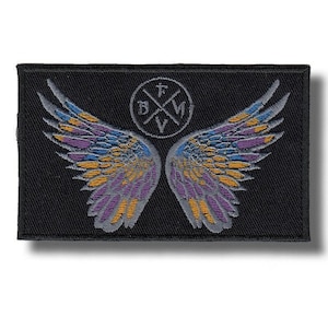Könnte beinhalten: Schwarzer rechteckiger Aufnäher mit einem Paar stilisierter Flügel in Lila, Blau und Gold. Ein kreisförmiges Emblem mit den Buchstaben "B", "F", "V" und "M" befindet sich mittig über den Flügeln. Für Kleidung oder Accessoires.