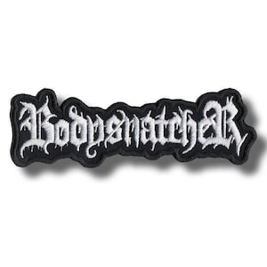 May include: A black embroidered patch with the word "Bodysnatcher" in white gothic lettering. The patch has a black border and is rectangular in shape. The text is stylized with sharp, pointed serifs.