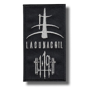 Puede incluir: Parche rectangular negro con diseño y texto bordados en blanco. El diseño presenta una forma estilizada sobre el texto "LAGUNACOIL" y "119". El parche tiene un borde negro y es probablemente para ropa o accesorios.