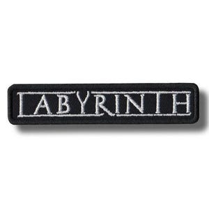 May include: Black rectangular patch with the word "LABYRINTH" embroidered in white. The patch has a white border and is likely for clothing or accessories.