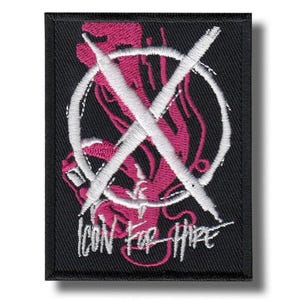 May include: Black embroidered patch with a pink graphic inside a white circle, crossed by a white 'X'. The text "ICON FOR HIRE" is embroidered in white below. The patch is rectangular in shape.