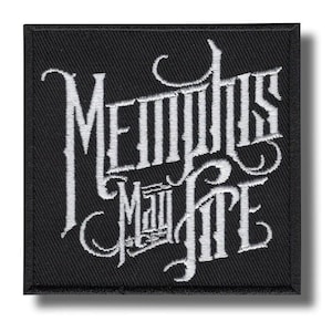 May include: Black square patch with white embroidered text reading "Memphis May Fire" in a stylized gothic font. The patch has a black border and a shadow effect.
