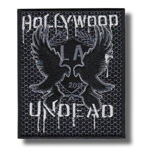 May include: Black and gray embroidered patch with the words "HOLLYWOOD UNDEAD" and "LA 2018". The patch features a central emblem with two stylized birds and a shield design.