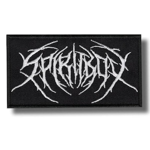 Op de afbeelding: Zwart rechthoekig embleem met de witte tekst "SPIRITBOX" in een gestileerd, gotisch lettertype. De tekst heeft een stekelig, doornig ontwerp. Het embleem is waarschijnlijk voor kleding of accessoires.