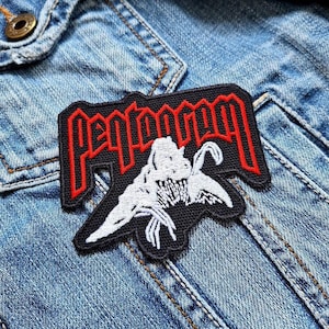 Può includere: Una toppa ricamata nera e rossa con la scritta "Pentagram" in lettere rosse stilizzate. La toppa presenta una grafica bianca di una creatura con le ali spiegate. La toppa è cucita su una giacca di jeans blu.