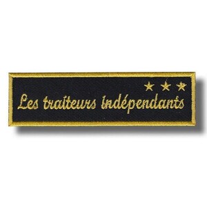 May include: A black embroidered patch with gold edging. The text "Les traiteurs indépendants" is embroidered in gold, accompanied by three gold stars. This patch is likely for a catering business or food service.