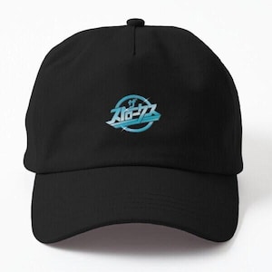 May include: Black baseball cap with a curved brim. The cap features a light blue and white graphic design with Japanese text in a circular emblem on the front. The design has a retro, futuristic aesthetic.