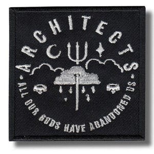 May include: Black square patch with white embroidered text and imagery. The text reads "ARCHITECTS" in an arc, with "ALL OUR GODS HAVE ABANDONED US" along the bottom. A trident, cloud, and rain design is in the center.