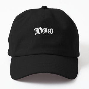 Op de afbeelding: Zwarte baseballpet met het woord "DIO" in witte gotische letters op de voorkant. De pet heeft een gebogen klep en een knoop aan de bovenkant. De hoed is gemaakt van een zacht, duurzaam materiaal.
