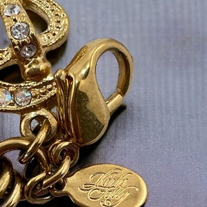 May include: Gold-tone charm bracelet with a gold-tone clasp and a small oval tag that reads "Kork's Folly".