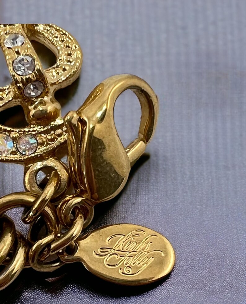 May include: Gold-tone charm bracelet with a gold-tone clasp and a small oval tag that reads "Kork's Folly".