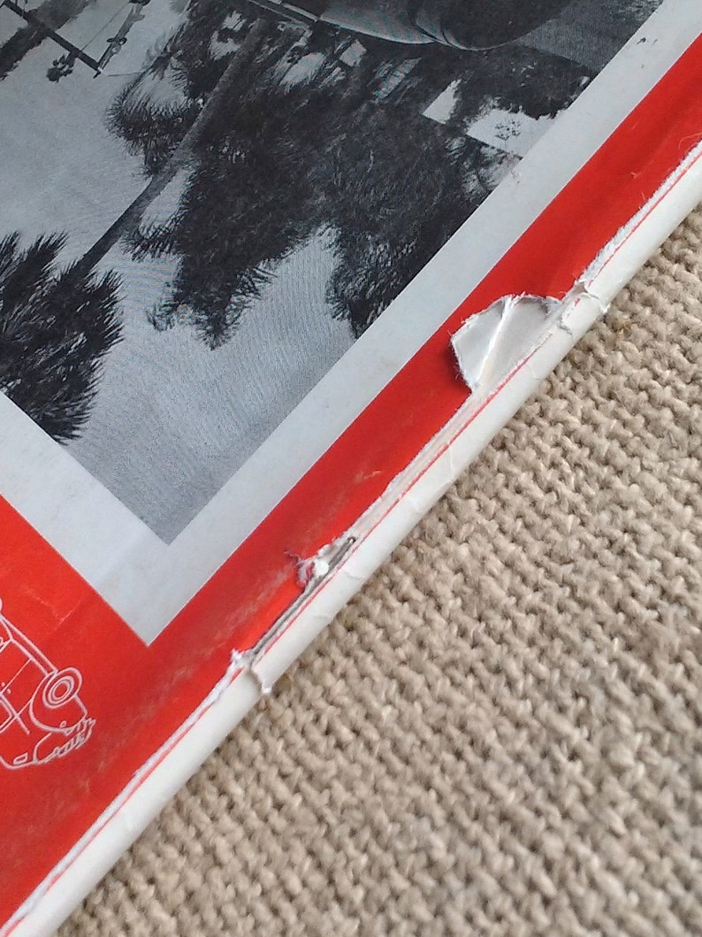 Pu&ograve; includere: Un libro rosso e bianco con un angolo di pagina strappato. Il libro ha una foto in bianco e nero di palme sulla copertina.