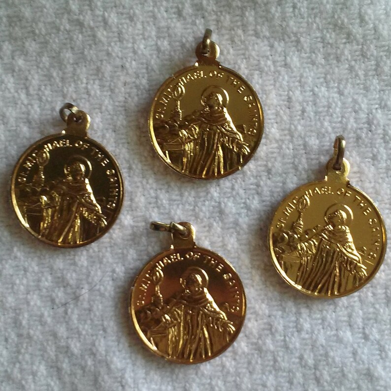 May include: Four gold-colored St. Michael of the Saints pendants. Each pendant features an image of a robed figure holding a staff, with the text "ST. MICHAEL OF THE SAINTS" around the edge. The pendants have a loop at the top for attaching to a chain.