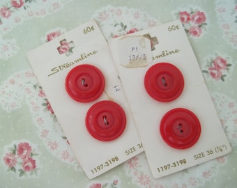 May include: Two cards of red plastic buttons, each card has four buttons. The cards are labeled "Streamline" and have the numbers "60¢" and "1197-3198" printed on them. The buttons are different sizes, one card has buttons labeled "Size 36 (1/4")" and the other card has buttons labeled "Size 36".